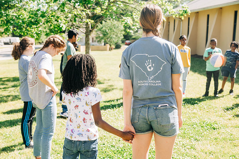 Children and Project Vida students playing a game together. 