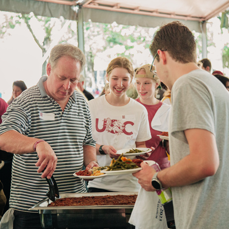 Students with their supporters dishing up southern comfort food during the 2023 SCHC Family Picnic.