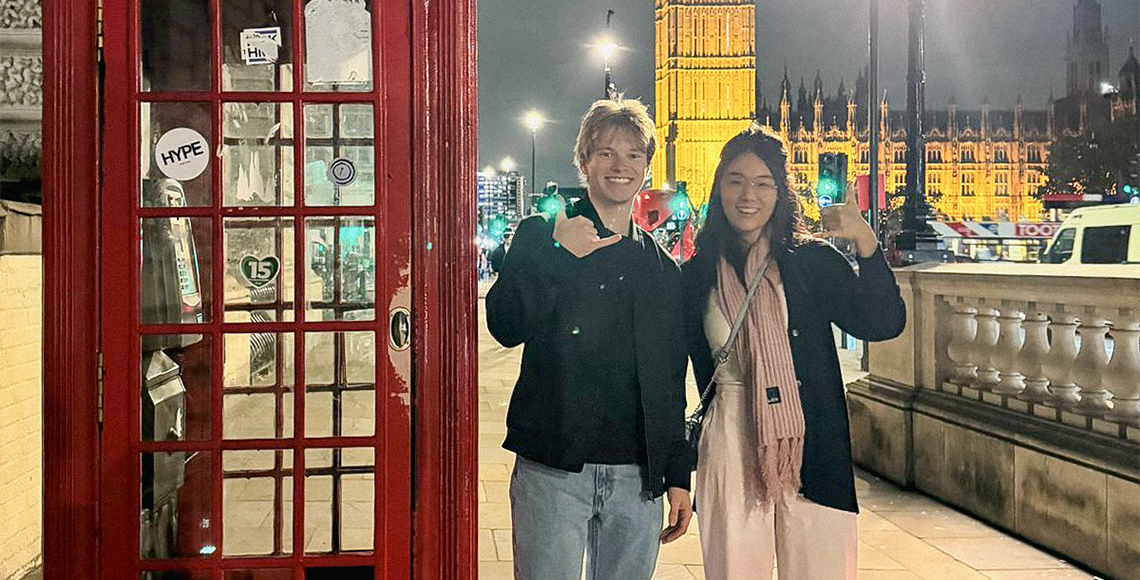 Students smiling next to a red telephone box with Big Ben in the background.