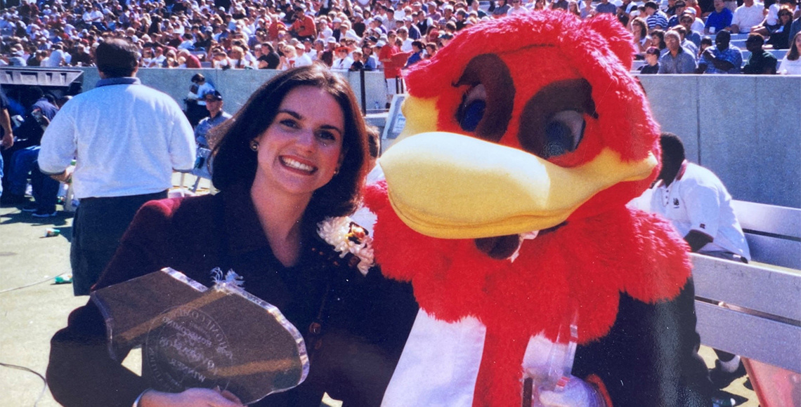 Smiling woman holding a clear plaque shaped like South Carolina next to USC's Cocky mascot.