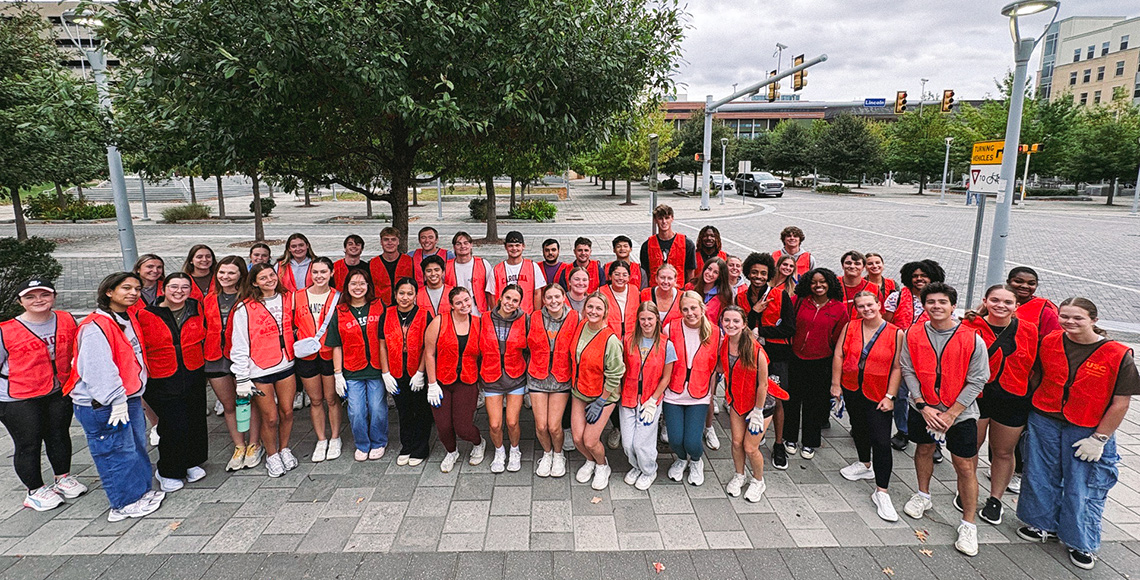 Group of students in neon orange service jackets.