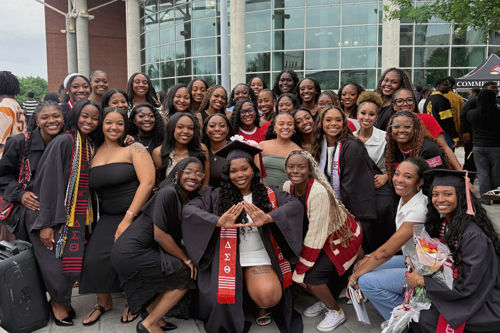 A group of students in graduation regalia smiling.