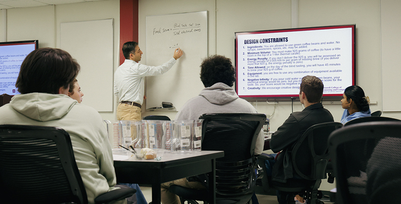 Instructor Zare writing on a white board in front of his students.