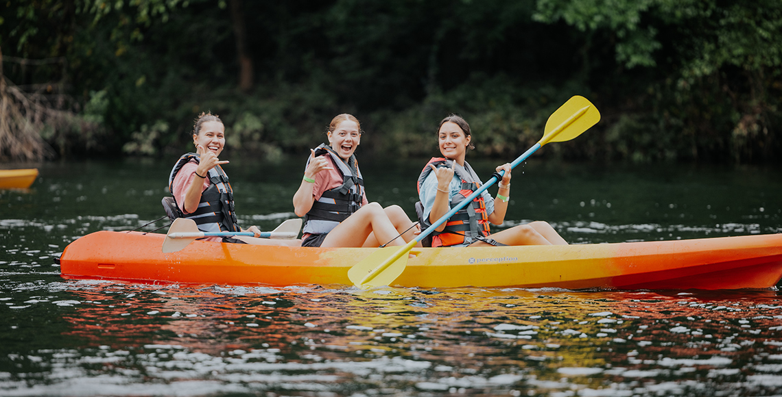 Students smiling as they kayak down the saluda river