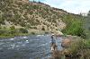 Will Morris stands in the river as a guide with a client who he is helping fly-fish.