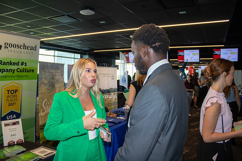 A student has a conversation with a recruiter from Goosehead Insurance at the Experience Expo.