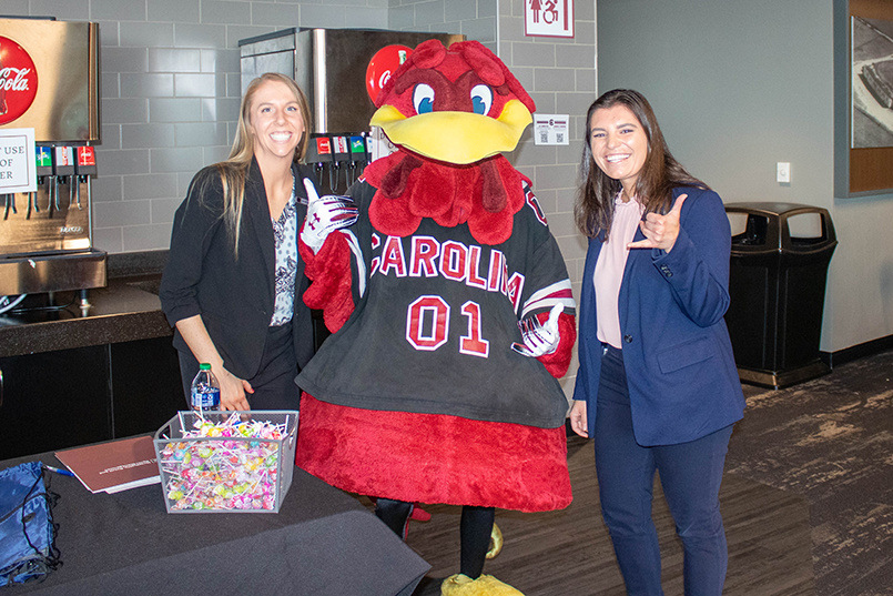 South Carolina mascot Cocky gives the Spurs Up sign while posing for a photo with two recruiters from Omni Hotels & Resorts at the Experience Expo.