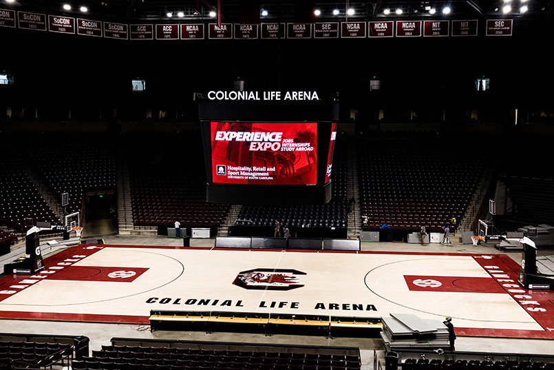 The video board at Colonial Life Arena displays a graphic for Experience Expo while hanging above the basketball court with a Block C logo in the center.