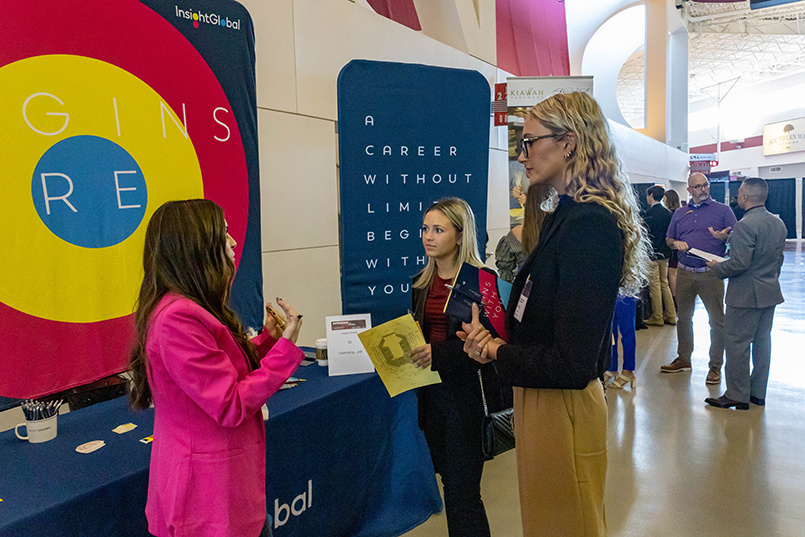 A representative from Insight Global speaks to a couple of student prospects at the Experience Expo job fair.