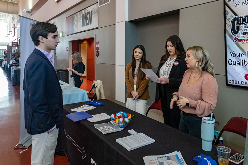 Three recruiters for Wyndham Destinations speak with a student about job opportunities.