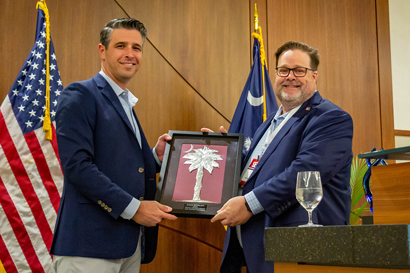 Department of Sport and Entertainment Management chair Matt Brown presents Adam Sperling, executive director of the 2022 President's Cup at Quail Hollow Club, with a plaque at the Sport Entertainment and Venues Tomorrow conference over Nov. 16-18, 2022, at the Columbia Metropolitan Convention Center.