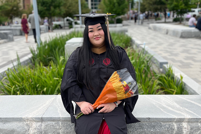 Miriam Feng poses in her cap and gown outside of Colonial Life Arena.