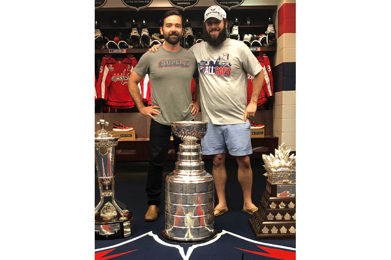 John Cosgrove stands with a colleague in front of the Stanley Cup