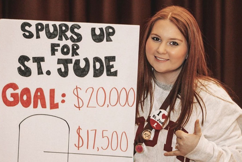 An HRSM student poses with a sign that says Spurs Up For St. Jude, Goal: $20,000, $17500.