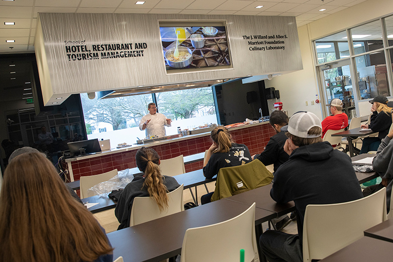 Chef instructor Robby Lybrand gives a lecture to student while giving a live demonstration of cooking techniques inside the J. Willard and Alice S. Marriott Foundation Culinary Laboratory.