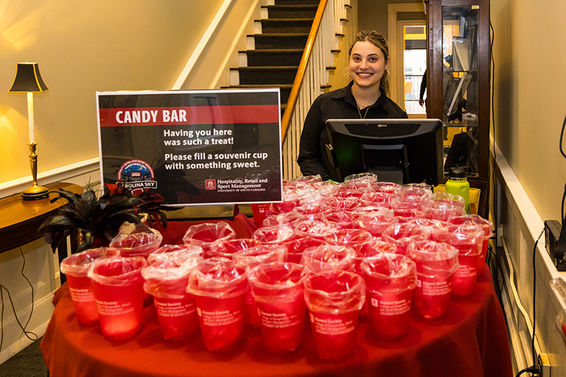 The candy bar with a sea of cups while an HRSM student working at McCutchen House smiles in the background.