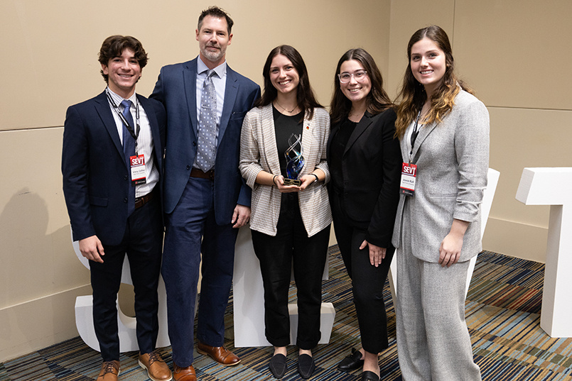 Five people pose for a photo after winning first place in the case competition
