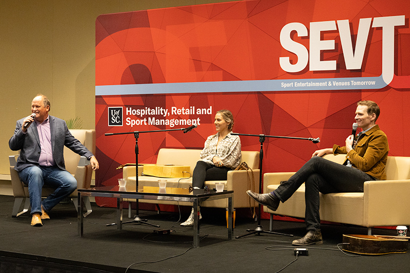 A moderator and two guest speakers on stage at SEVT