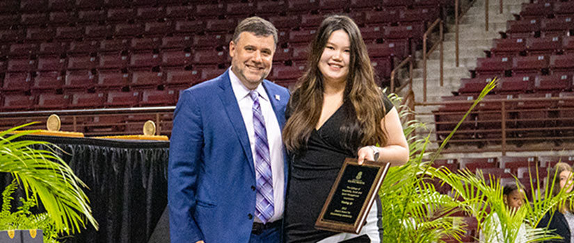 Yiming Qi stands with Interim Dean David Cardenas while receiving her College of HRSM Leader award.