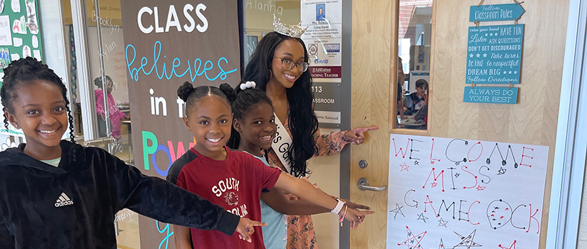Jordyn Lewis points at a sign welcoming her to an elementary school where she was a guest speaker.