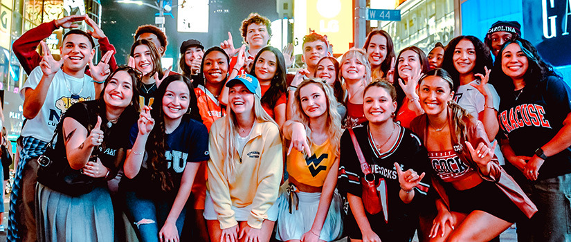 A large group of college students attending New York Fashion Week pose for a photo together in Times Square.