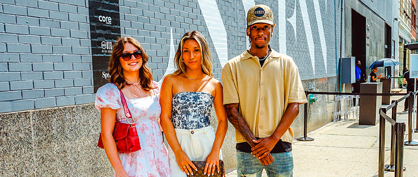 Alden Rissel, Misa Malkin and Jalen Clark pose for a photo on the sidewalk while attending New York Fashion Week.