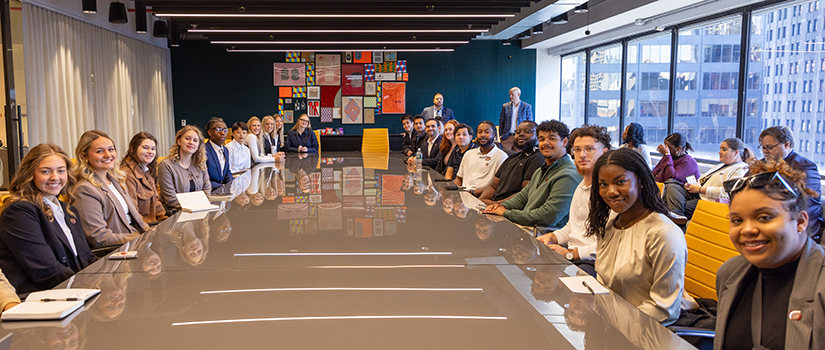 Students pose at a board meeting table at Wasserman