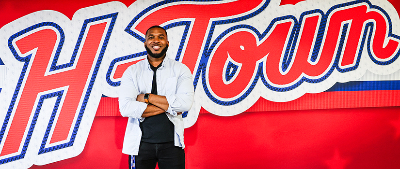 Duane Scott poses in front of an H Town inscription