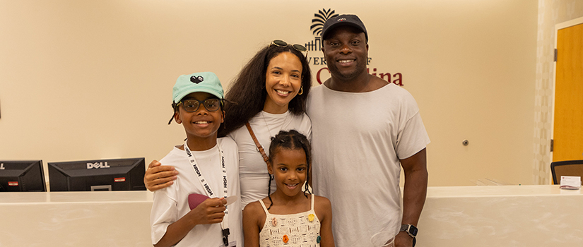 Ayo Akinsete and his family smile in the HRSM Welcome Center lobby during his campus visit.