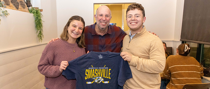 Murray Cohn poses with two University of South Carolina students holding a Smashville T-shirt during a dinner celebration event.