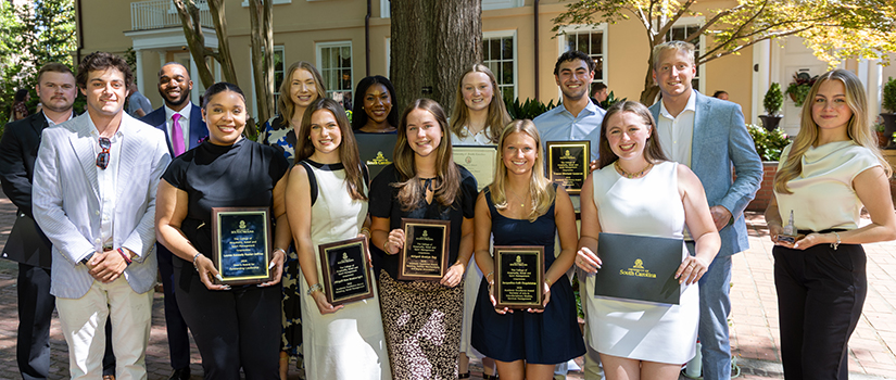 HRSM students pose outdoors with plaques and certificates after being recognized for academic excellence, leadership and senior awards at USC Awards Day.