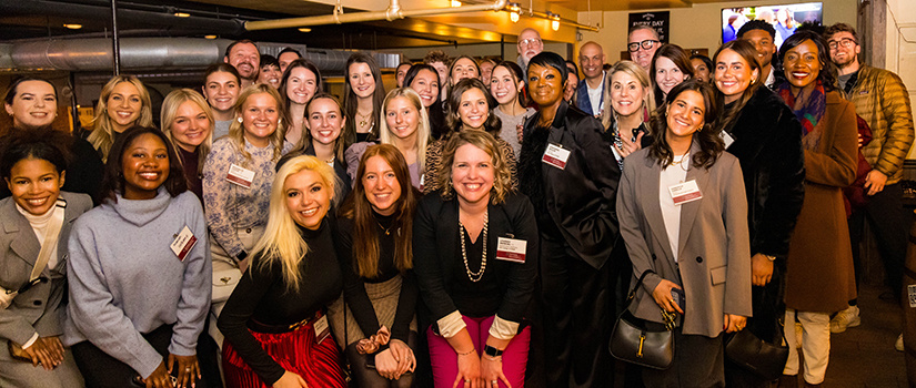 A large group of people pose for a photo in New York City for an alumni event.