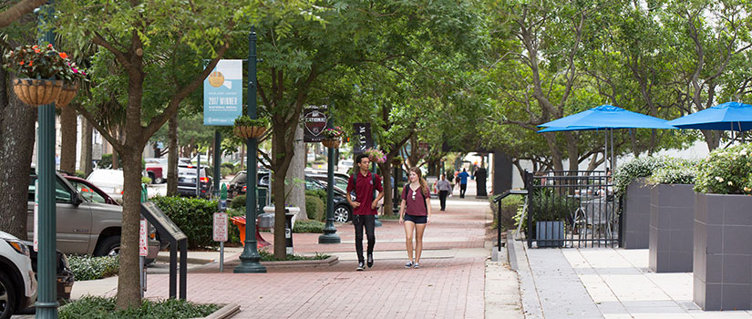 Two students walk along Main Street, bordered by flowers, trees and cafes, in Columbia, S.C.