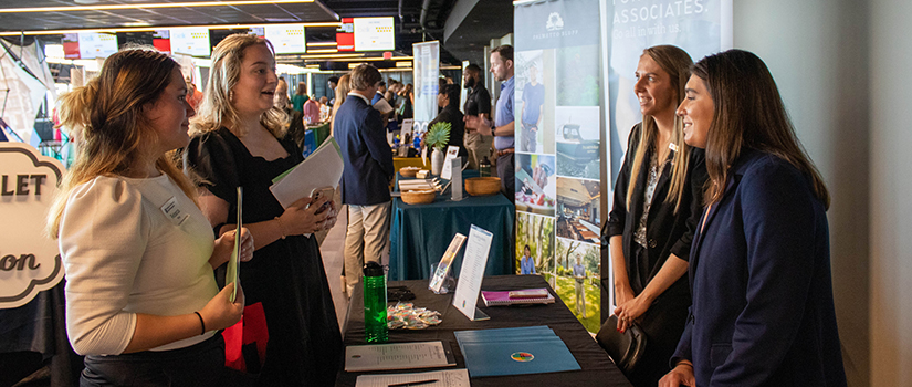 Two students speak with company representatives at the fall 2022 Experience Expo.