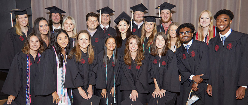 A group of 2022 HRSM Leaders Program graduates pose for a photo in caps and gowns.