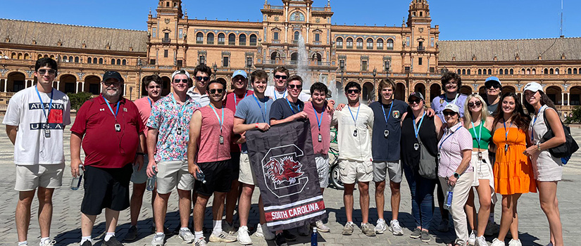 Students hold a South Carolina Gamecocks flag while posing for a photo in Spain.