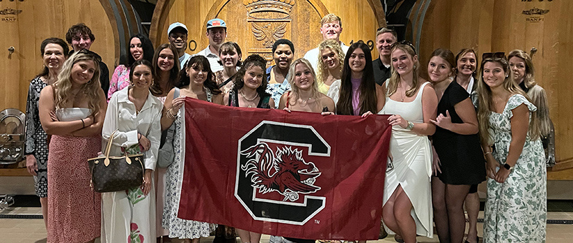Students, faculty and staff pose for a photo with the Block C Gamecock flag while visiting a winery in Italy during a Maymester study abroad trip.