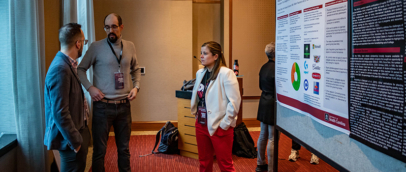 Three attendees at the CSRI conference discuss a research paper being presented.