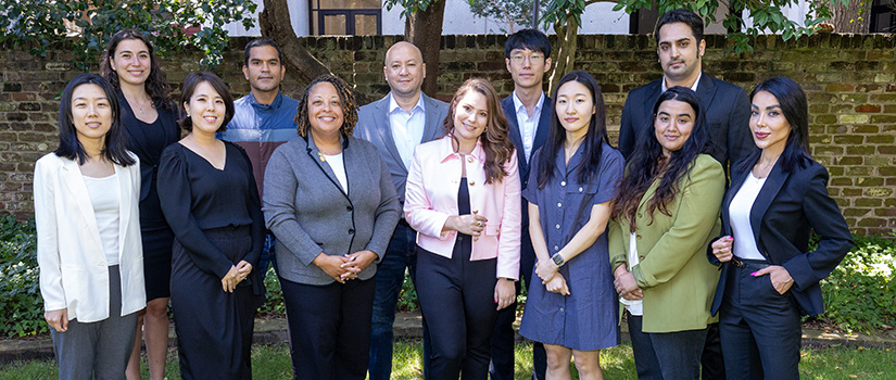 Members of the Ph.D. in hospitality management program pose for a photo in a garden alongside director Kathy Kim.
