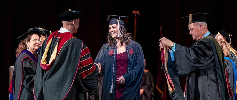 A student shakes hands with faculty at the HRSM Degrees of Excellence ceremony.
