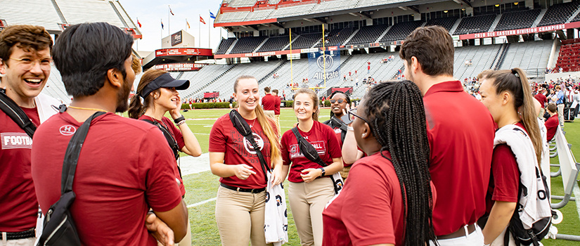 A group of students talk and laugh on the field at Williams-Brice Stadium prior to the 2022 Garnet & Black Spring Game.