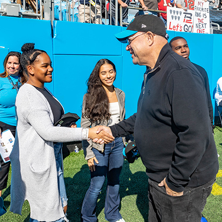 David Tepper shakes hands with Sydney Rhue at a Carolina Panthers game.