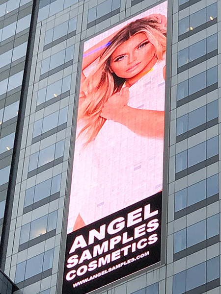 Augusta Roach is featured on a billboard advertisement on a building for Angel Samples Cosmetics.