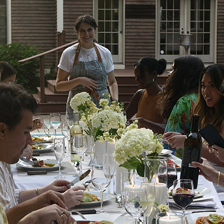 Maria Colalancia standing at head of table with guests