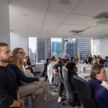 Students in a board room listening to a presentation