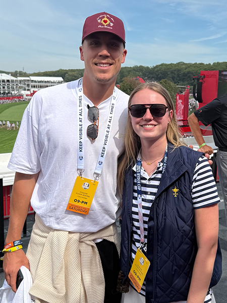Caitlin Cassidy poses with professional basketball player Duncan Robinson on a viewing platform overlooking the Ryder Cup course.