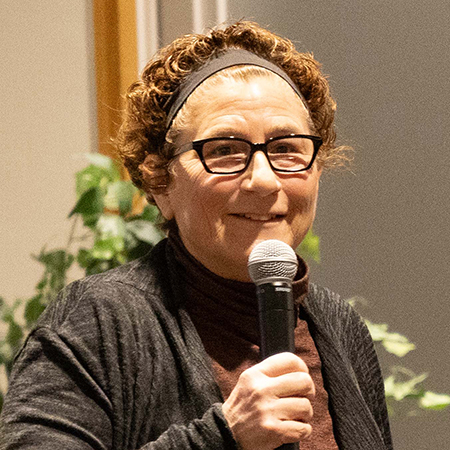 Michelle Delloso holds a microphone while speaking to a group