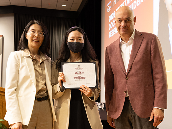 Mina Kim holds Outstanding Doctoral Student Researcher award certificate with faculty presenters