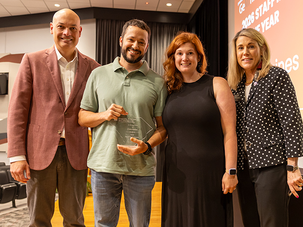 Chris Raines recognized as Staff Member of the Year holding award with colleagues