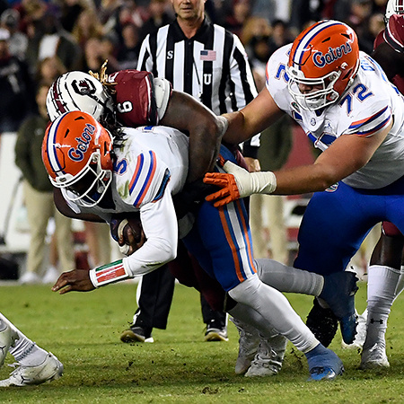 A Florida Gator football player is tackled by a player from South Carolina.